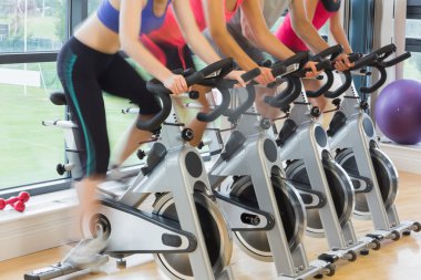 Mid section of people working out at spinning class clipart