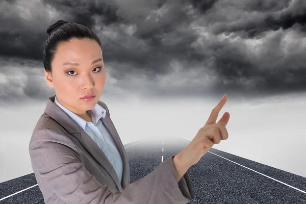 Composite image of unsmiling asian businesswoman pointing — Stock Photo, Image