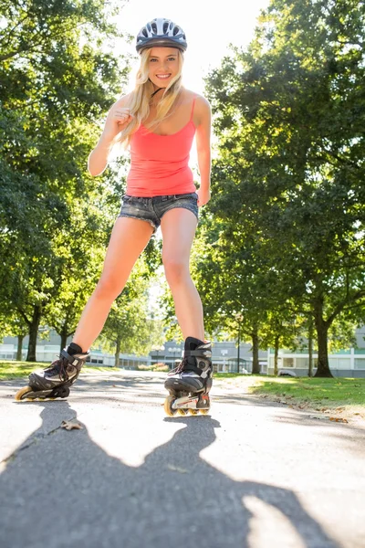 Casual sonriente rubia patinaje en línea en el camino — Foto de Stock