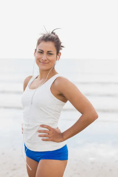 Woman listening to music through earphones at beach — Stock Photo, Image