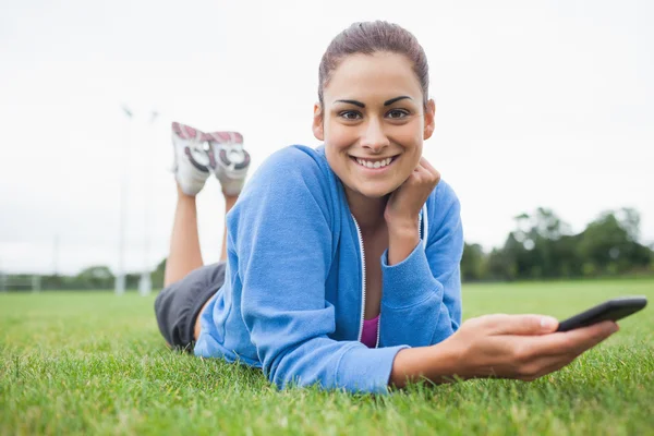 Pretty woman with mobile phone lying on grass — Stock Photo, Image