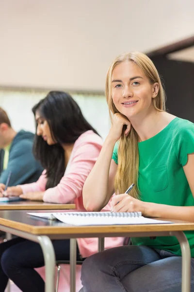 Student with others writing notes in classroom — Stock Photo, Image