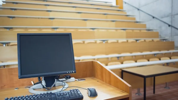 Computer monitor with empty seats in a lecture hall — Stock Photo, Image