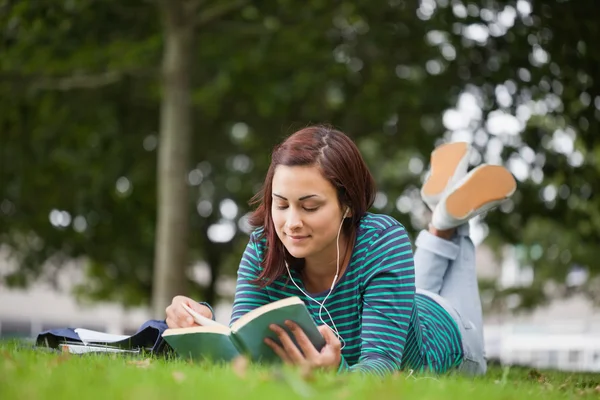 Calma estudante casual deitado na leitura grama — Fotografia de Stock