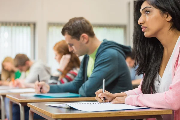 Unga studenter skriva noter i klassrummet — Stockfoto