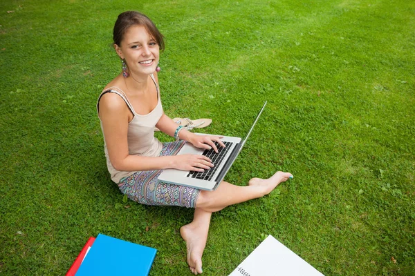 Student using laptop with books at the park — Stock Photo, Image