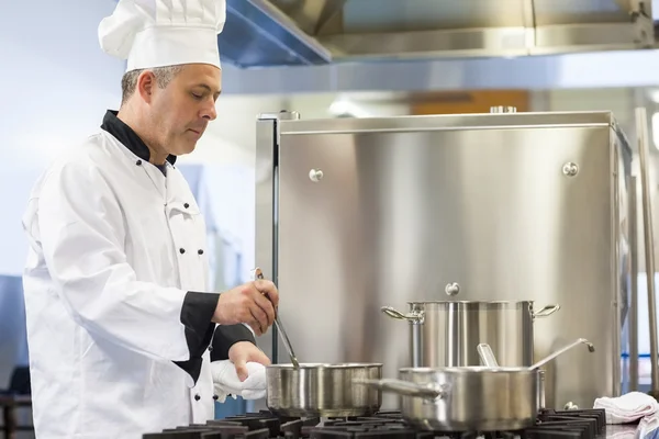 Focused head chef stirring in pot — Stock Photo, Image