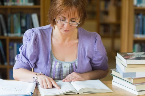 Mature female student studying at desk in the library — Stock Photo, Image