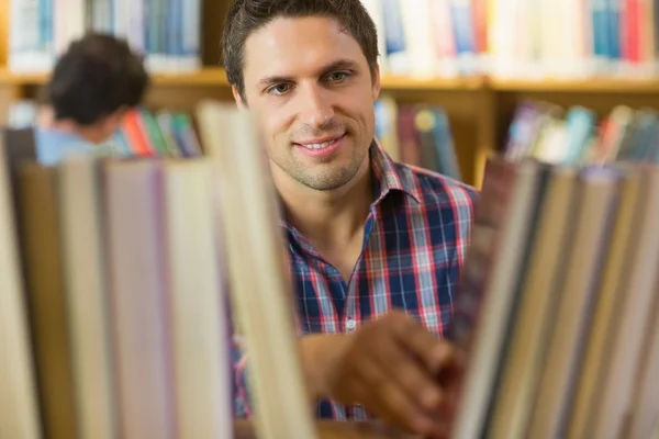 Mature student selecting book from shelf in the library — Stock Photo, Image