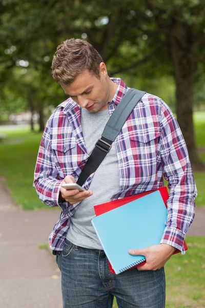 Bonito estudante casual de pé e mensagens de texto — Fotografia de Stock