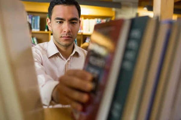 Mogen student att välja bok hylla i biblioteket — Stockfoto