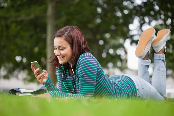 Lachende casual student liggend op gras texting — Stockfoto