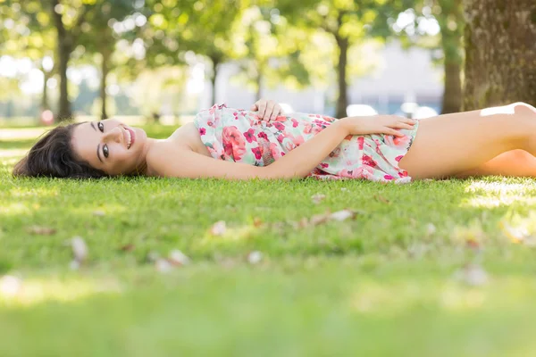 Morena feliz elegante deitada em um gramado — Fotografia de Stock