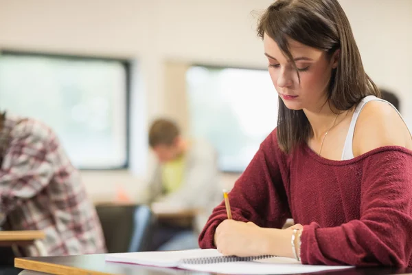 Student skriver anteckningar i klassrummet — Stockfoto