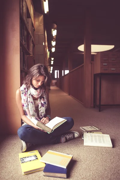 Estudante mulher lendo um livro no corredor da biblioteca — Fotografia de Stock
