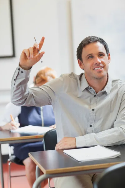 Lachende knappe volwassen student zijn hand verhogen — Stockfoto