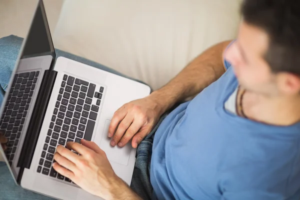 Vista de ángulo alto del hombre casual usando el ordenador portátil sentado en el sofá —  Fotos de Stock