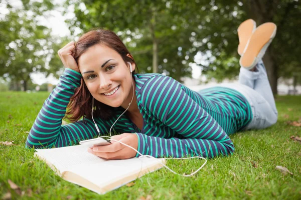 Happy casual student lying on grass listening to music — Stock Photo, Image