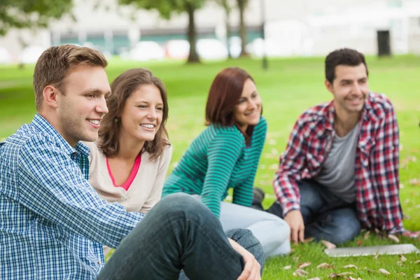 Casual happy students sitting on the grass laughing — Stock Photo, Image