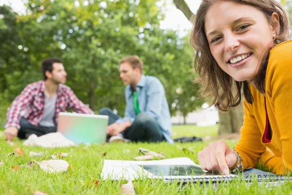 Student met tablet pc terwijl mannetjes met laptop in park — Stockfoto