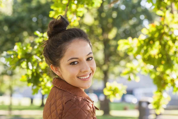 Cute brunette woman wearing a brown coat posing in a park — Stock Photo, Image