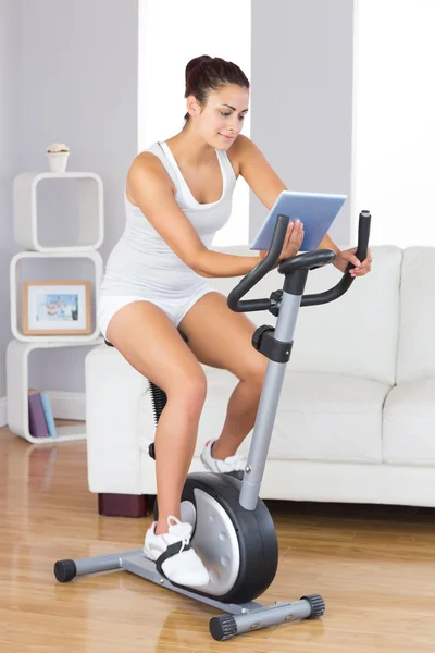 Contenido mujer delgada usando su tableta durante el entrenamiento —  Fotos de Stock