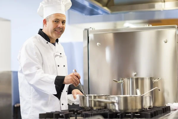 Smiling head chef stirring in pot — Stock Photo, Image