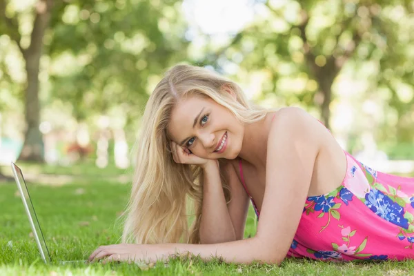 Retrato de mulher linda usando seu caderno deitado em um gramado — Fotografia de Stock