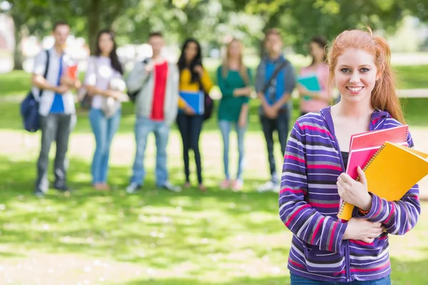 Školy dívka drží knihy se studenty v parku — Stock fotografie