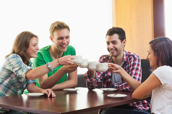 Quatro estudantes casuais bebendo uma xícara de café — Fotografia de Stock