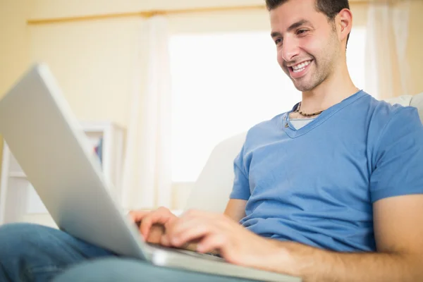 Casual aantrekkelijke man zittend op de Bank met behulp van kijken naar laptop — Stockfoto