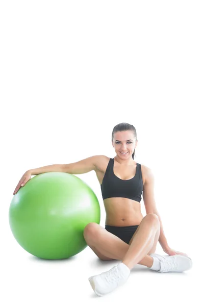 Mujer morena posando sentada junto a una pelota de ejercicio — Foto de Stock