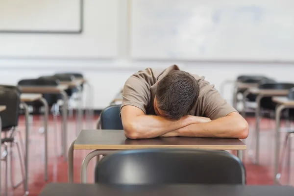 Hombre maduro estudiante recostado su cabeza sobre el escritorio mientras duerme —  Fotos de Stock