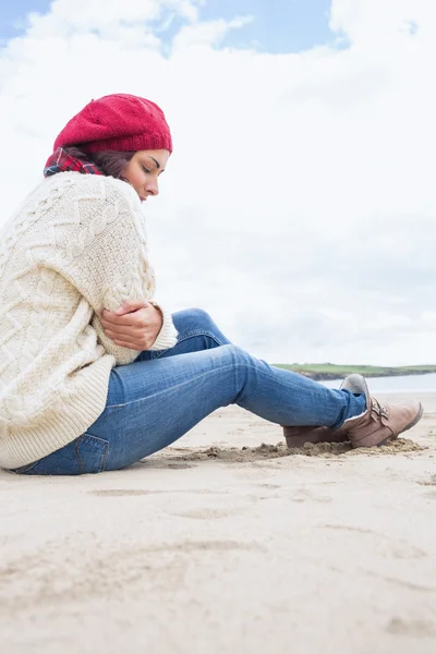 Kvinna i elegant varma kläder sitter på stranden — Stockfoto