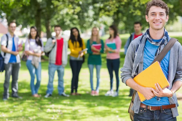 Colegial sosteniendo libros con estudiantes en el parque — Foto de Stock