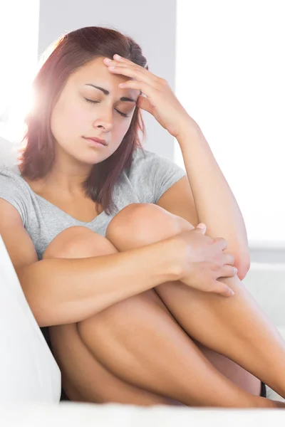 Upset beautiful woman sitting on her couch — Stock Photo, Image