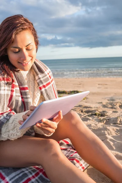 Vrouw bedekt met deken gebruiken, tablet pc op strand — Stockfoto