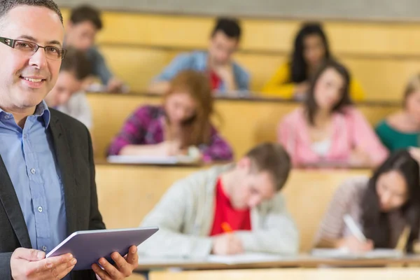 Lärare som använder TabletPC med studenter som sitter på föreläsning hall — Stockfoto