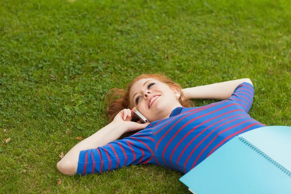 Gorgeous smiling student lying on grass phoning — Stock Photo, Image