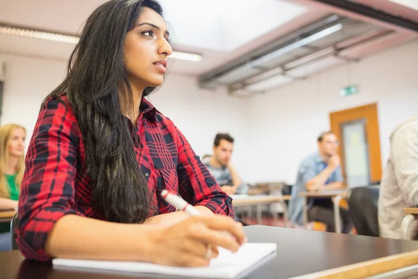 Female student with others writing notes in classroom — Stock Photo, Image