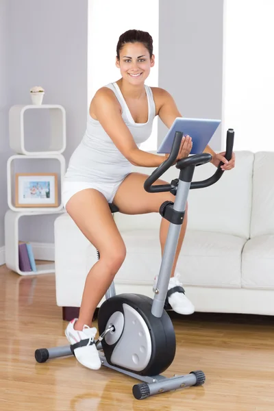 Mulher de treinamento feliz usando uma bicicleta de exercício — Fotografia de Stock