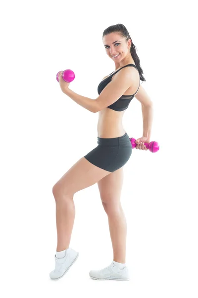 Side view of smiling active woman training with dumbbells Stock Picture