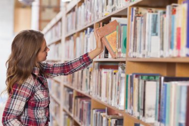 Pretty student placing book in shelf clipart