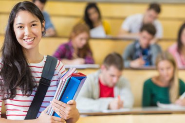 Smiling female with students sitting at the lecture hall clipart