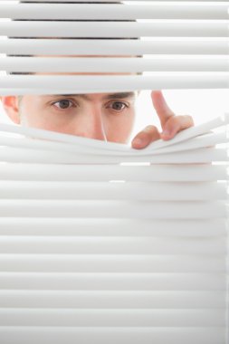 Serious male eyes spying through roller blind clipart