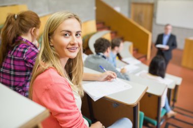 Smiling female with students and teacher at lecture hall clipart