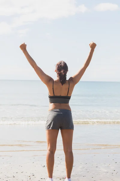 Frau hebt die Arme am Strand stehend — Stockfoto