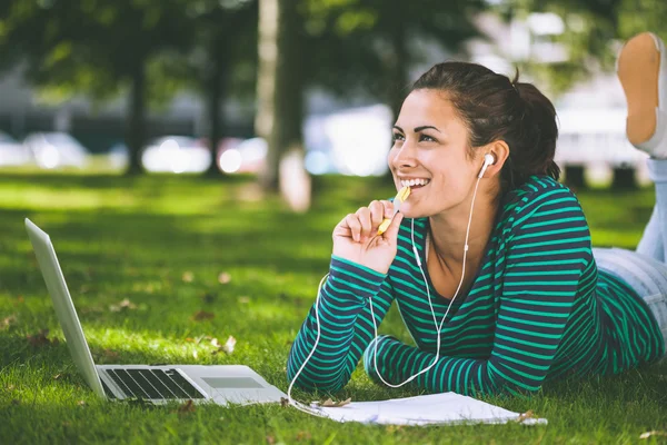 Ridere studente casuale sdraiato sull'erba prendere appunti — Foto Stock