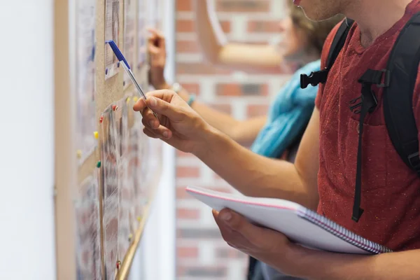 Estudantes casuais procurando algo no quadro de avisos — Fotografia de Stock