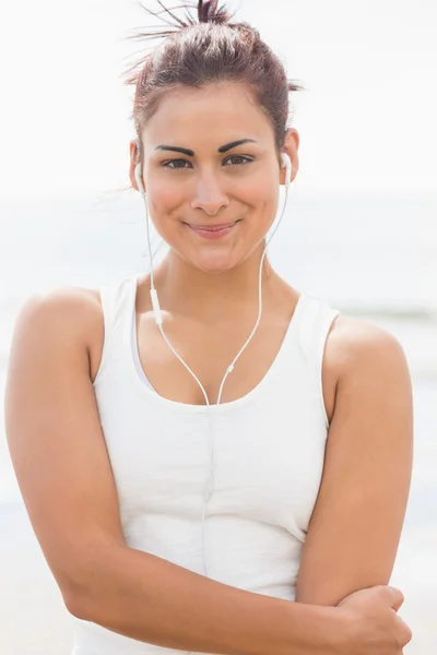 Schöne lächelnde Frau hört Musik am Strand — Stockfoto